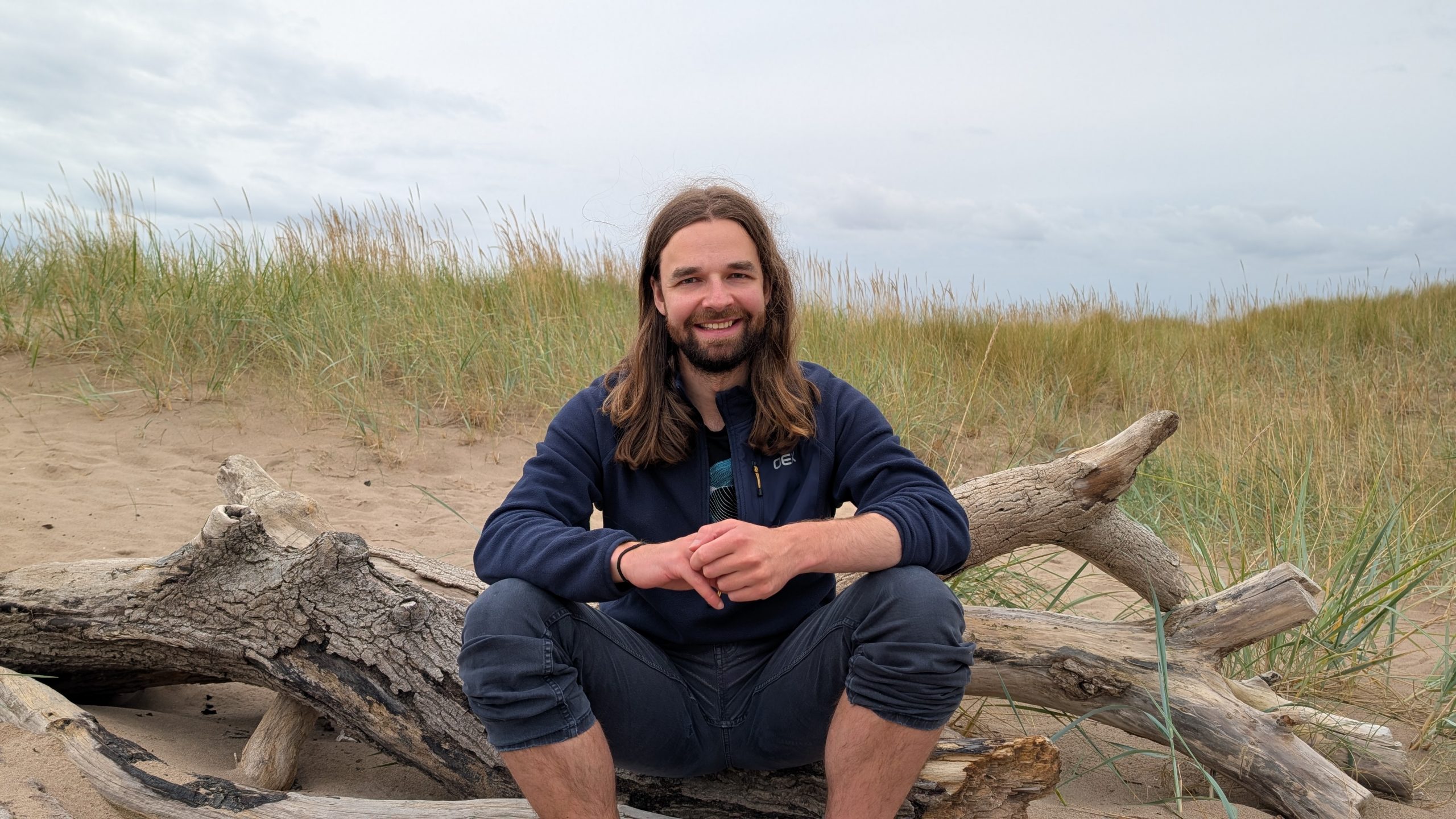 Person sitting on a piece of wood in the dunes